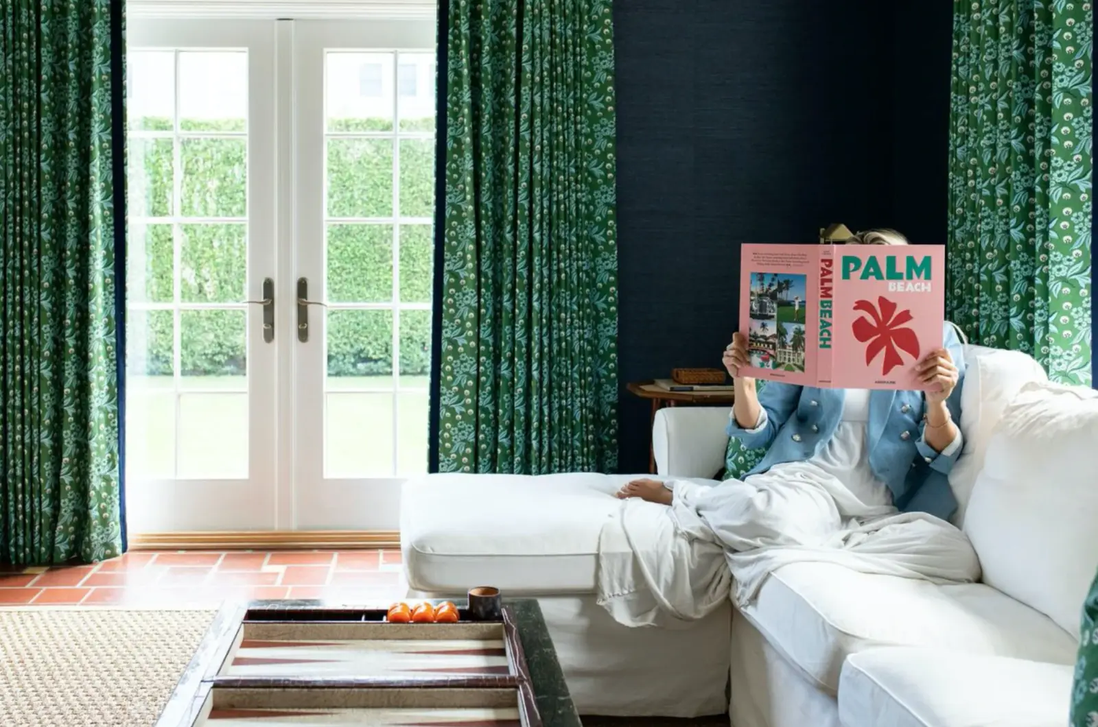 Navy grasscloth den with green floral curtains and a white sectional