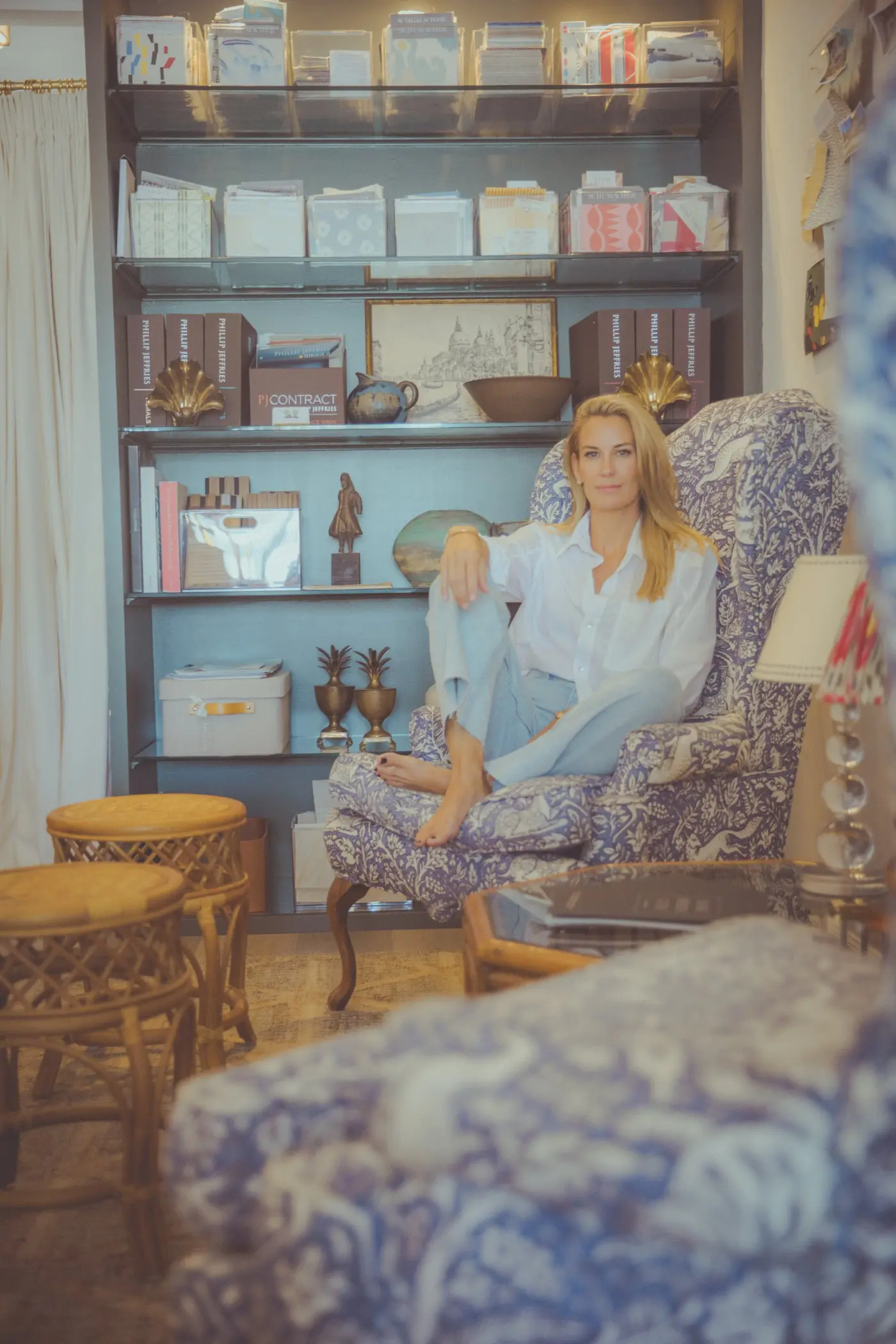Libby Lary seated in a blue block-print wingchair in the studio