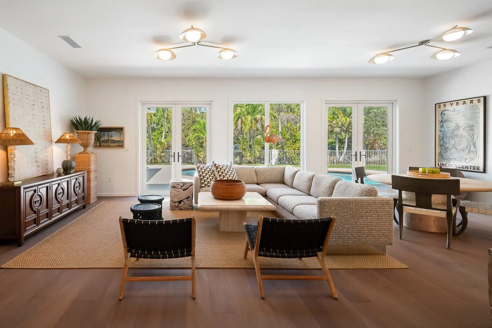 Open living room with woven leather chairs looking out to a pool