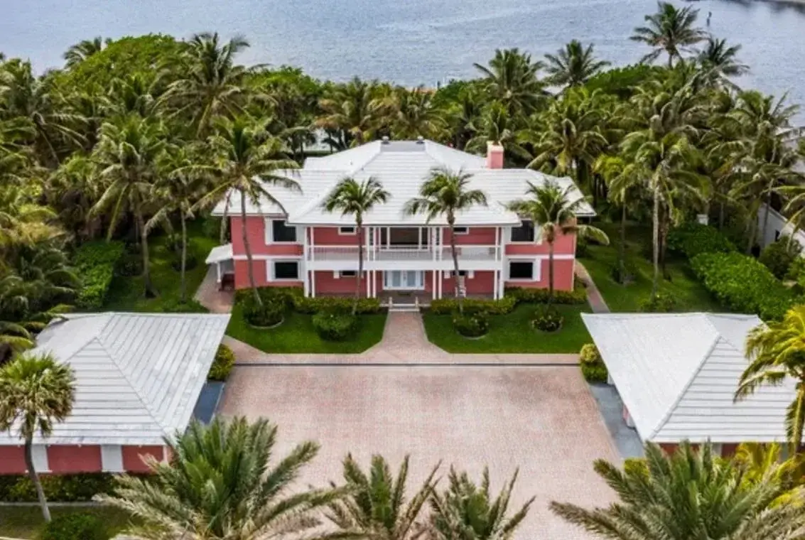 Aerial view of a coral-pink waterfront estate ringed by palms