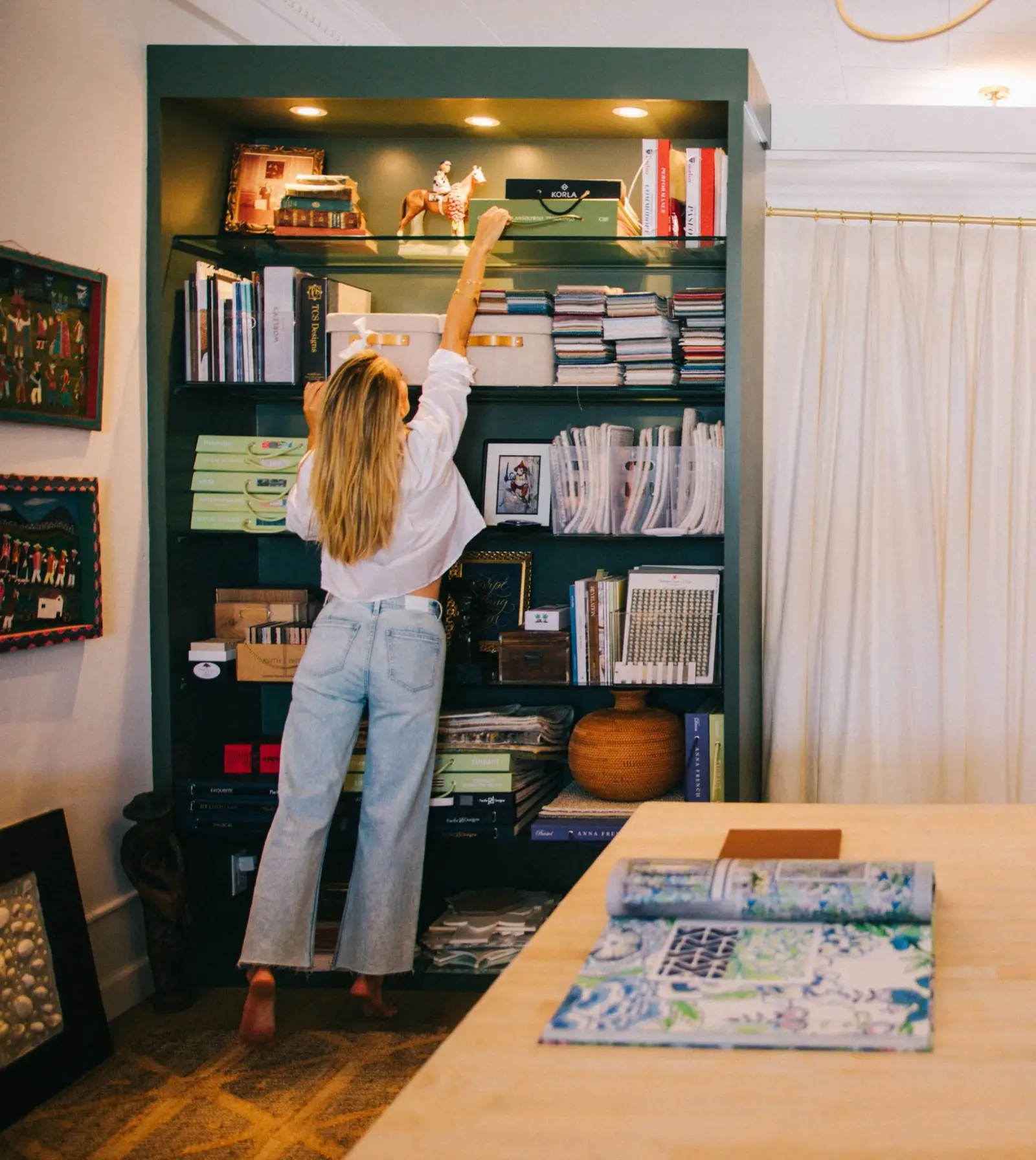 Inside the Elizabeth Gray Homes studio, reaching for fabric samples on the green shelves